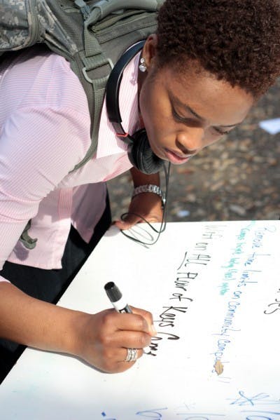 Second-year religion major Jessica Virgille, 19, writes her request for completely wireless dorms on the Unite Party slate platform on Turlington Plaza on Monday. "If we can have it [wireless] out here, we can have it everywhere," Virgille said.