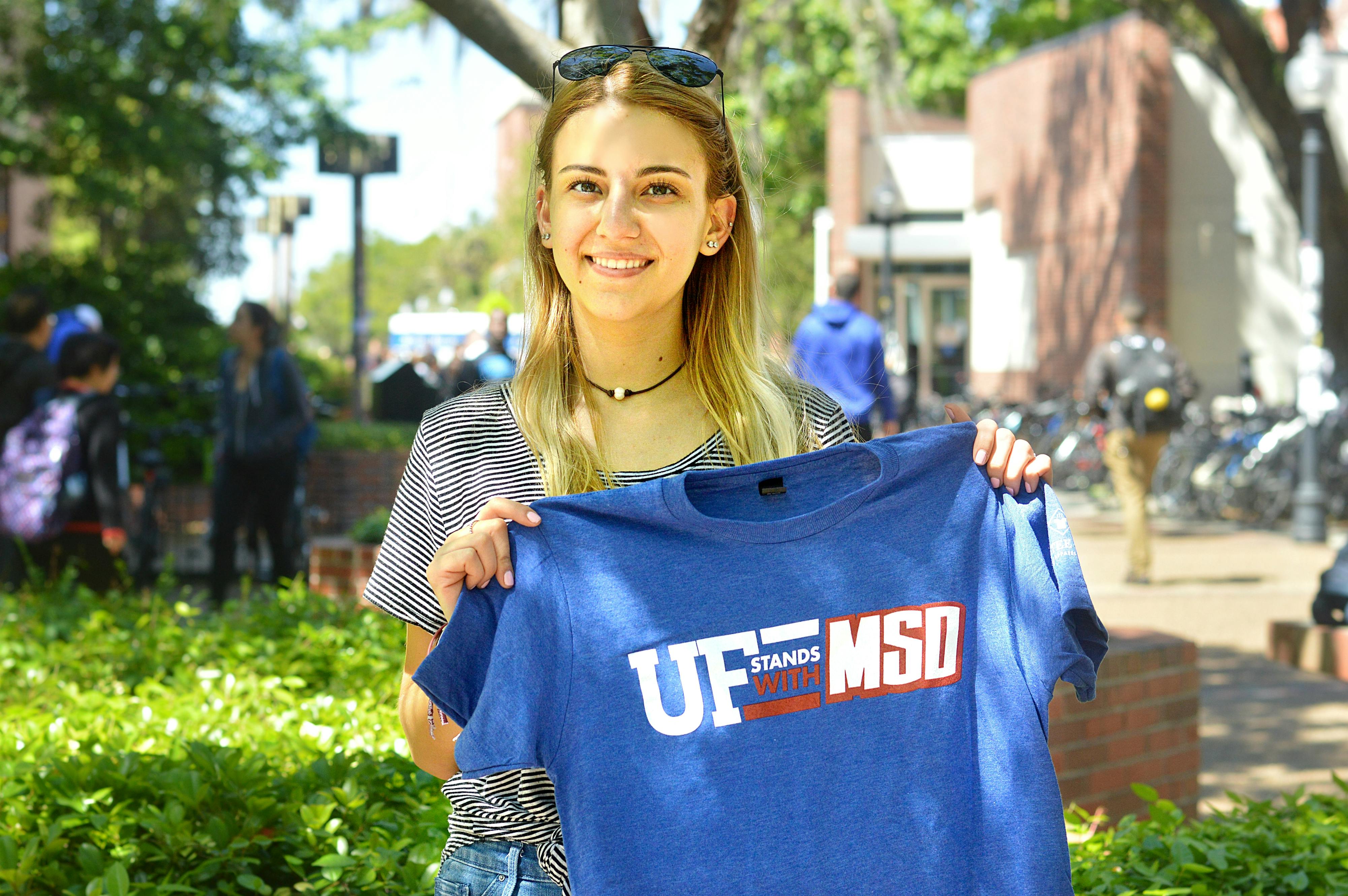 Julia Tiplea, a 19-year-old marine science sophomore, hands out "UF stands with MSD" T-shirts to fundraise for her group's trip to Washington for the national "March for Our Lives" event Saturday.