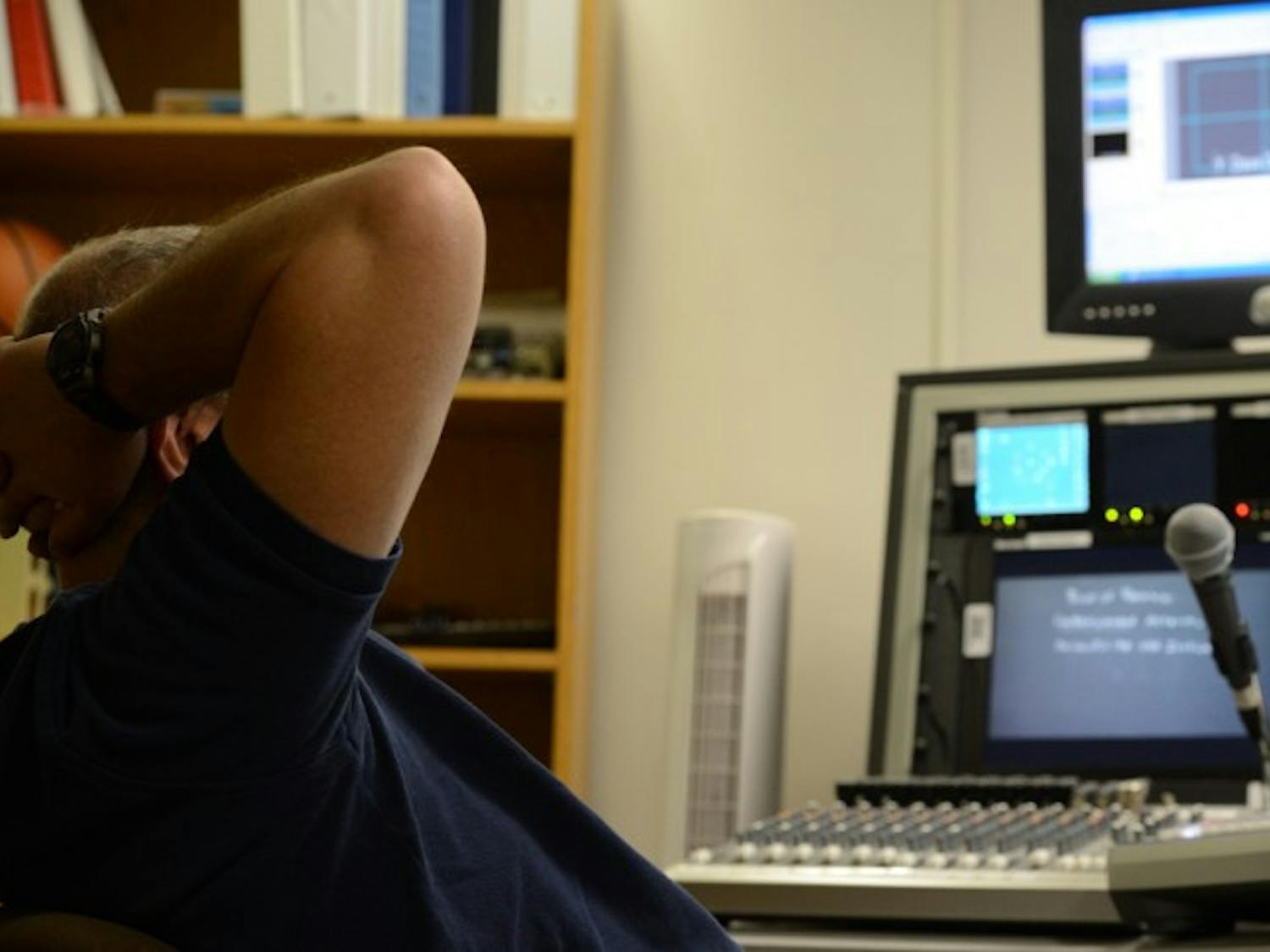 Anthony Bouton, known to most as “The Director,” lounges at his control panel as he films professor Mark Rush’s microeconomics class Friday morning.