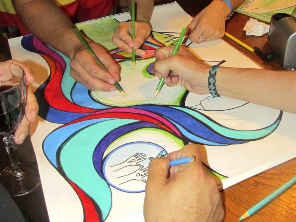 UF students in the Latino Hispanic Organization of Graduate Students sketch the plans for the mural they painted on the 34th Street Wall in memory of women killed in Latin America.