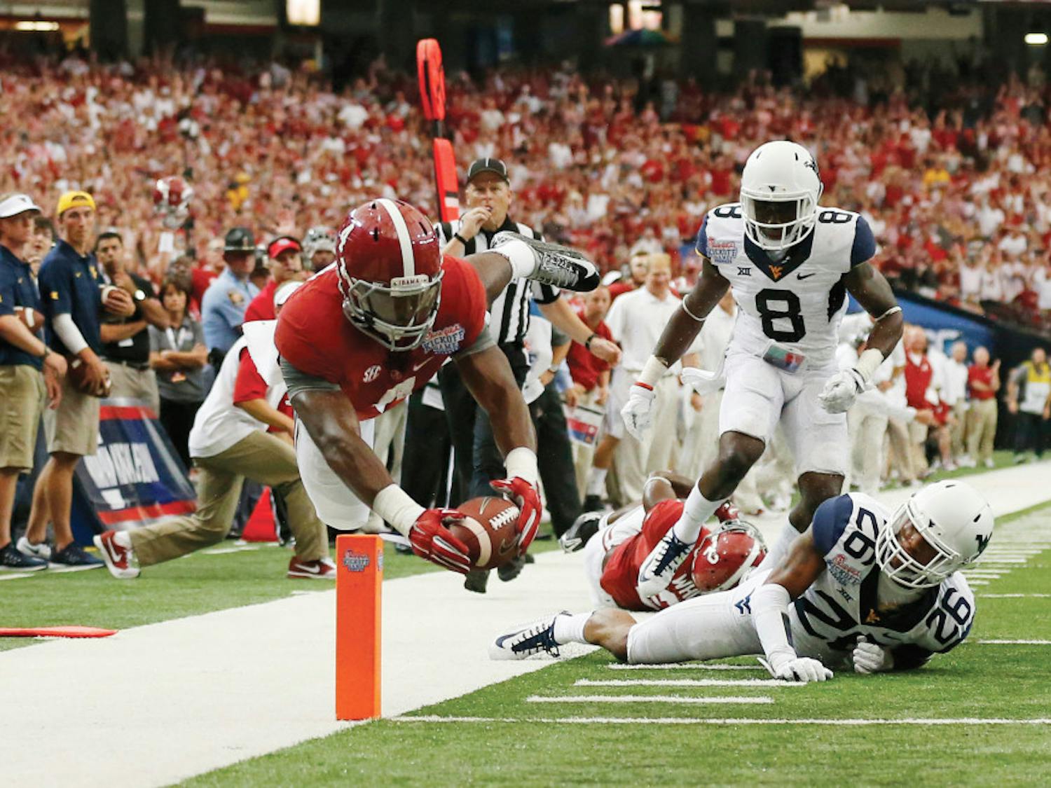 Alabama running back T.J. Yeldon (4) dives into the end zone for a touchdown as West Virginia's Travis Bell (26) and Karl Joseph (8) defend in the first half of an NCAA college football game Saturday, Aug. 30, 2014, in Atlanta.