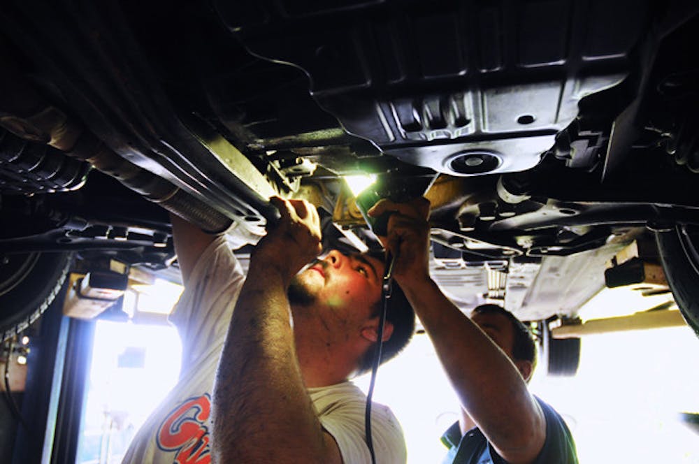 <p>Santa Fe freshman Nick Vlacos, left, works on the intake manifold while full-time instructor Kirk Lapan, right, shines a light under a raised car at the Dignity Project Complex, 1125 SE Fourth St., on Wednesday.</p>