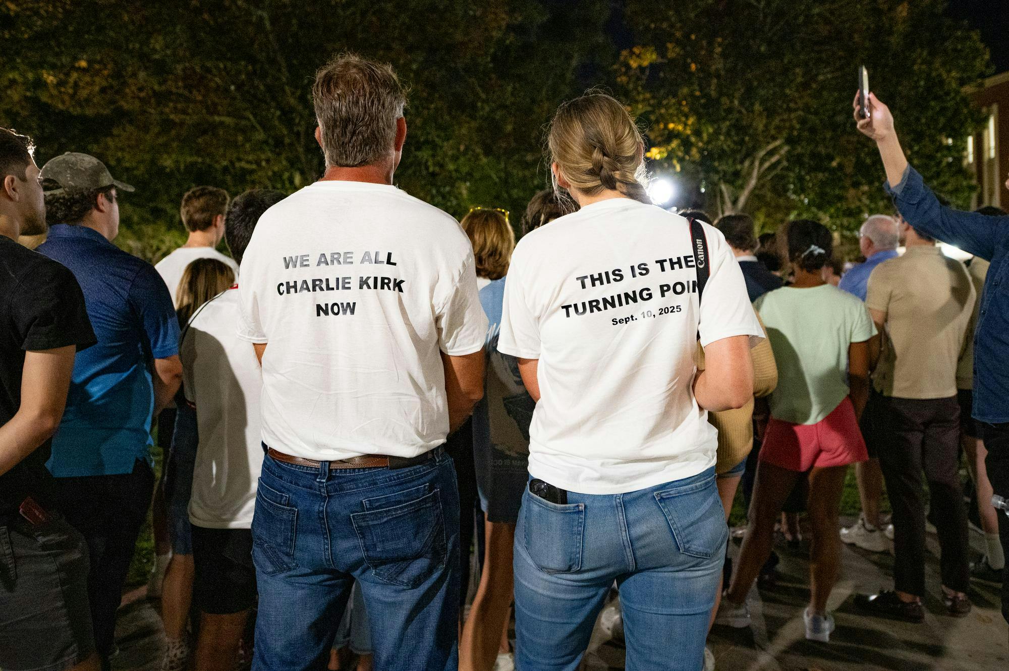 Two people in matching shirts stand during a vigil in memorium of Charlie Kirk on Thursday, Sept. 11, 2025.