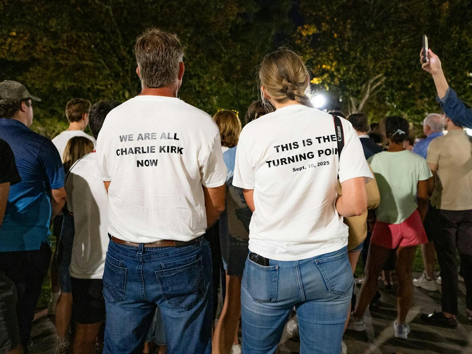 Two people in matching shirts stand during a vigil in memorium of Charlie Kirk on Thursday, Sept. 11, 2025.