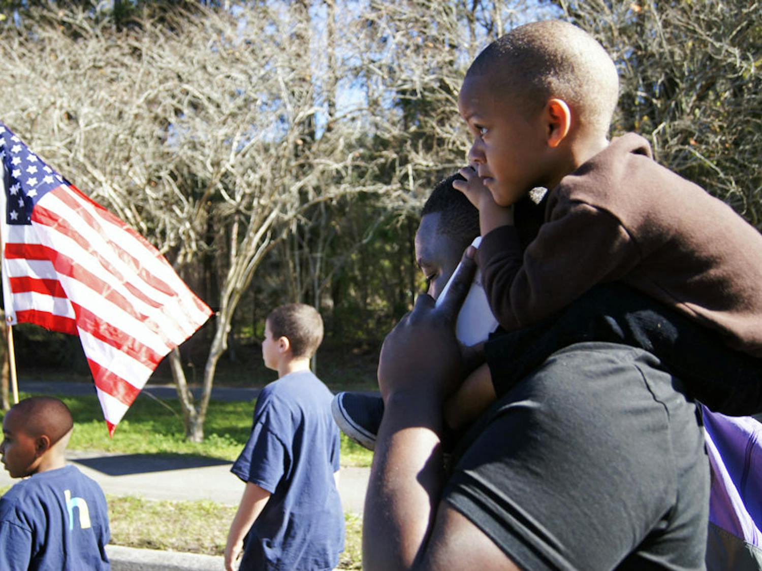 27-year-old Ushie Alungbe, a barber and dog breeder, carries his nephew, Kani Strickland, 3, on his shoulders as they take part in the King Celebration Annual Commemorative March held Monday in honor of Dr. Martin Luther King Jr.