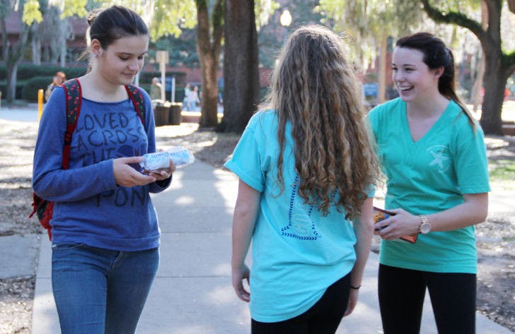 Natasha Stanisic, an 18-year-old UF computer engineering freshman, receives free cookies from Brittany Jacquay, an 18-year-old UF freshman, and Caitlyn Turner, an 18-year-old UF psychology freshman, Monday on the Plaza of the Americas. The Theta Alpha sorority sisters wanted to “spread God’s love in a practical way.”
