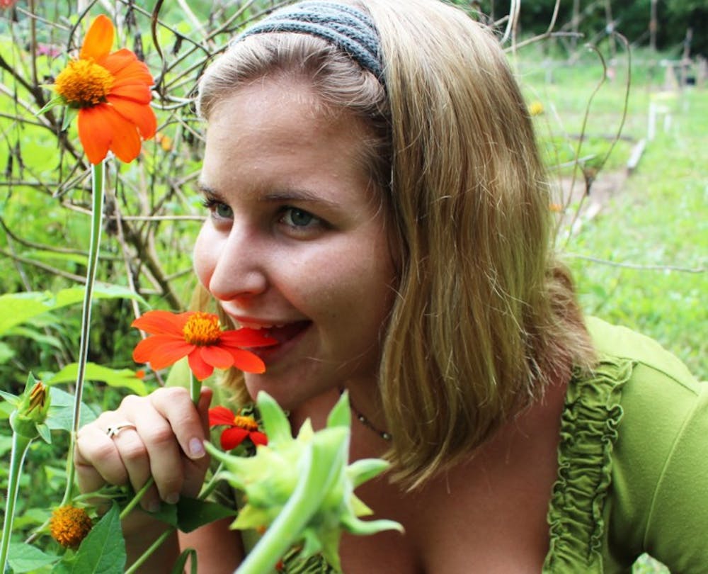 <p>Kelly Korman, a 23-year-old women’s studies graduate student and president of Eternally Edible Landscaping Club, eats a nasturtium flower on Monday at the Student Agricultural Gardens on Museum Road.</p>