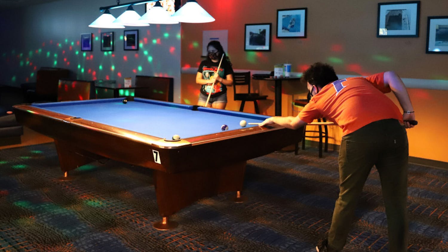 Max Slabbinck (right), 22, a senior media and society student, and Averi Hemingway, 21, a recent telecommunication graduate, shoot pool at the Reitz Union Game Room on Oct. 10, 2020. To ensure social distancing, the two pool tables nearest to Slabbinck and Hemingway are covered and face masks are required at all times.