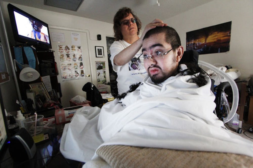 <p>Timothy Bird, 23, gets a haircut from his mother, Dee Bird, in their west Gainesville apartment Feb. 5. Timothy attended UF for two semesters, studying microbiology and then history.</p>