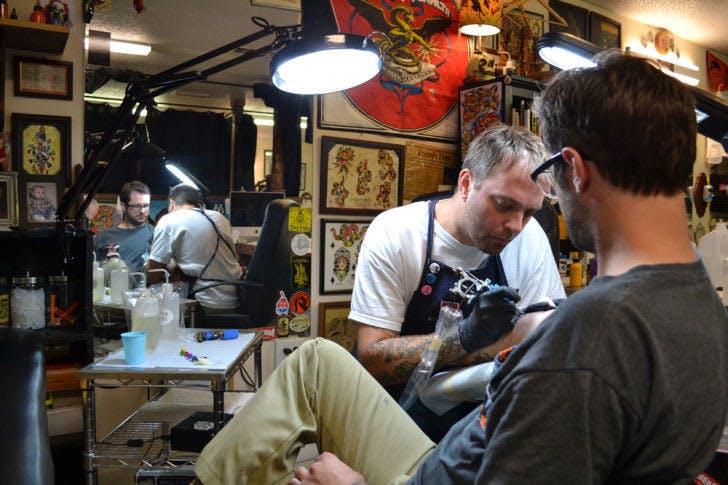 Mike Salay, 39, owner of Anthem Tattoo Parlor, tattoos Rich Mal, 29, the shop’s tattoo apprentice. The parlor is relocating April 15 to 230 NW Second Ave.