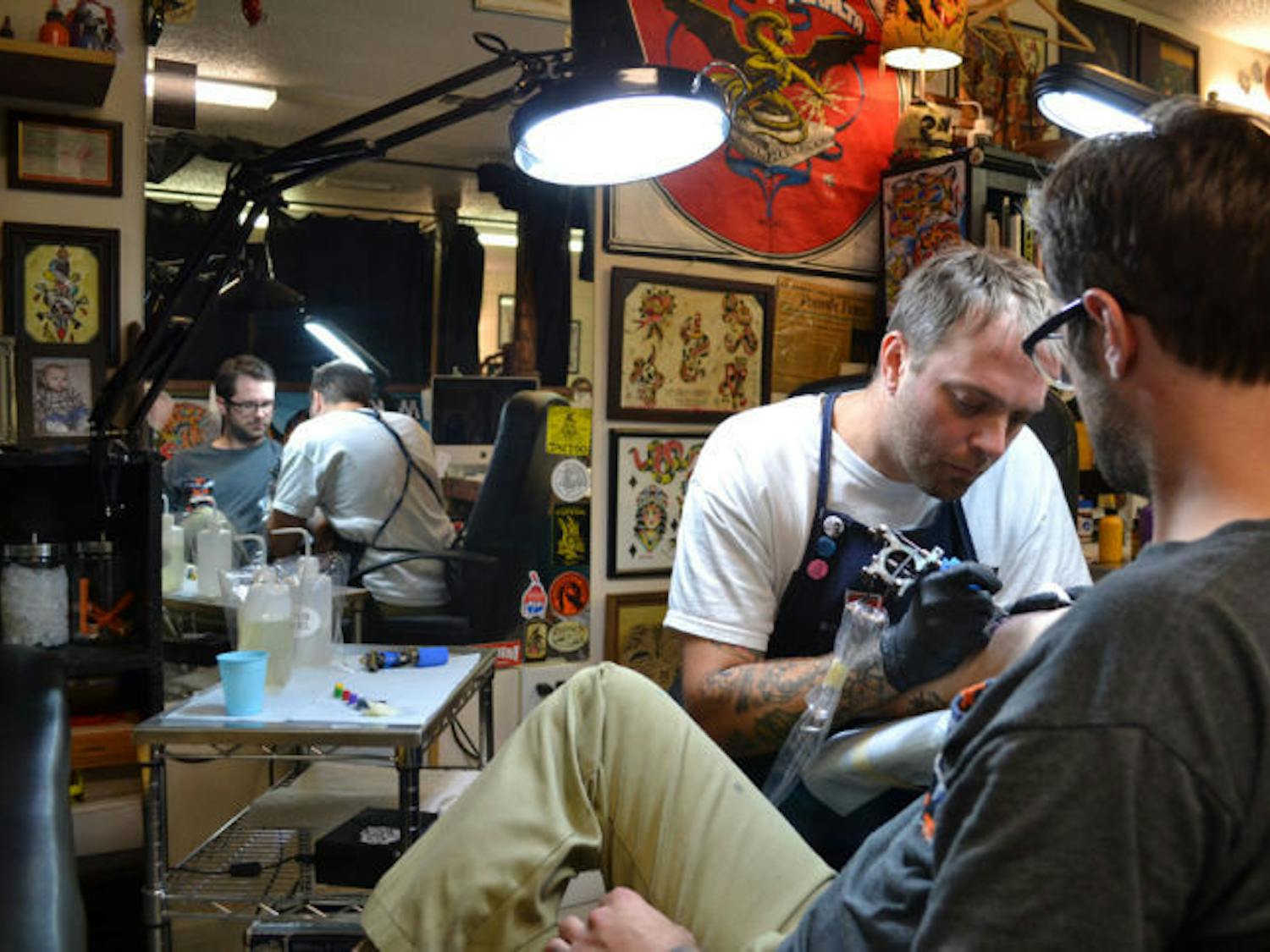 Mike Salay, 39, owner of Anthem Tattoo Parlor, tattoos Rich Mal, 29, the shop’s tattoo apprentice. The parlor is relocating April 15 to 230 NW Second Ave.