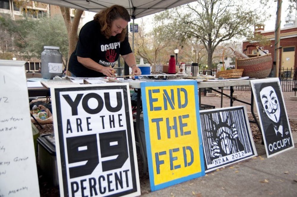 <p>Occupy supporter Annette Gilley, 58, makes a poster on Bo Diddley Community Plaza on Tuesday for "Occupy the Courts," an event that will take place Jan. 20.</p>