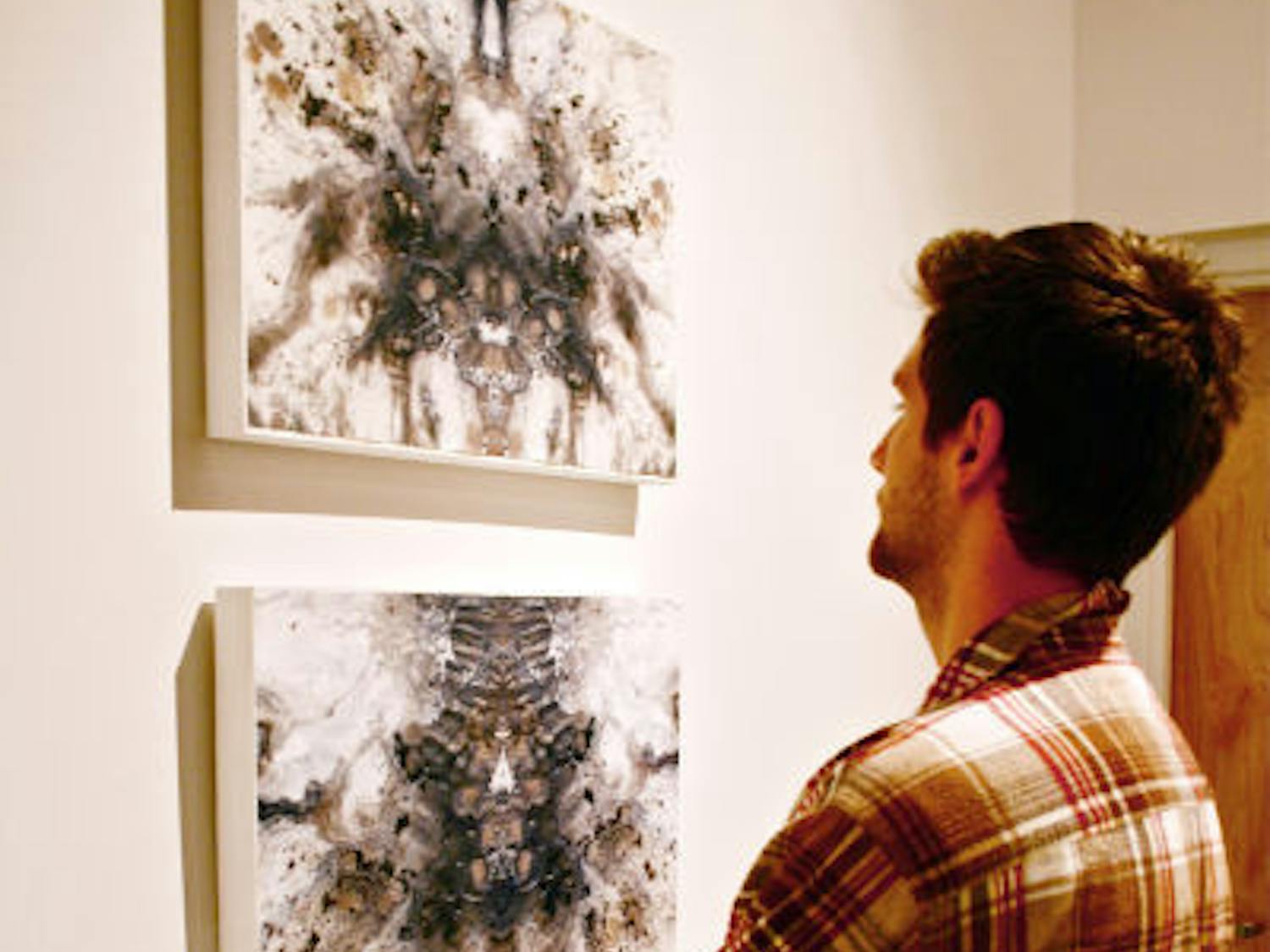 Drawing senior Domenic Henderson,21, admires the work of fellow artist Alexa Udermann, a drawing senior, at the WARPhaus gallery. The artists’&nbsp; work will be on display through Feb. 6.