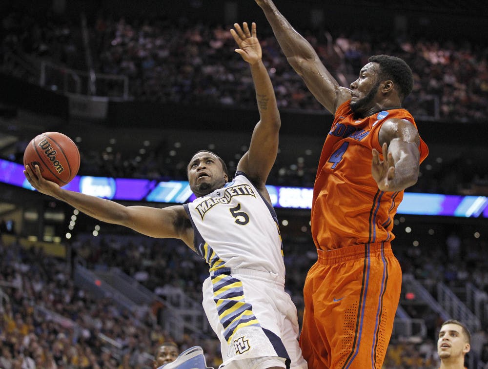 Marquette's Junior Cadougan (5) falls away as he shoots against Florida's Patric Young during the first half of an NCAA men's college basketball tournament West Regional semifinal on Thursday, March 22, 2012, in Phoenix. (AP Photo/Chris Carlson)