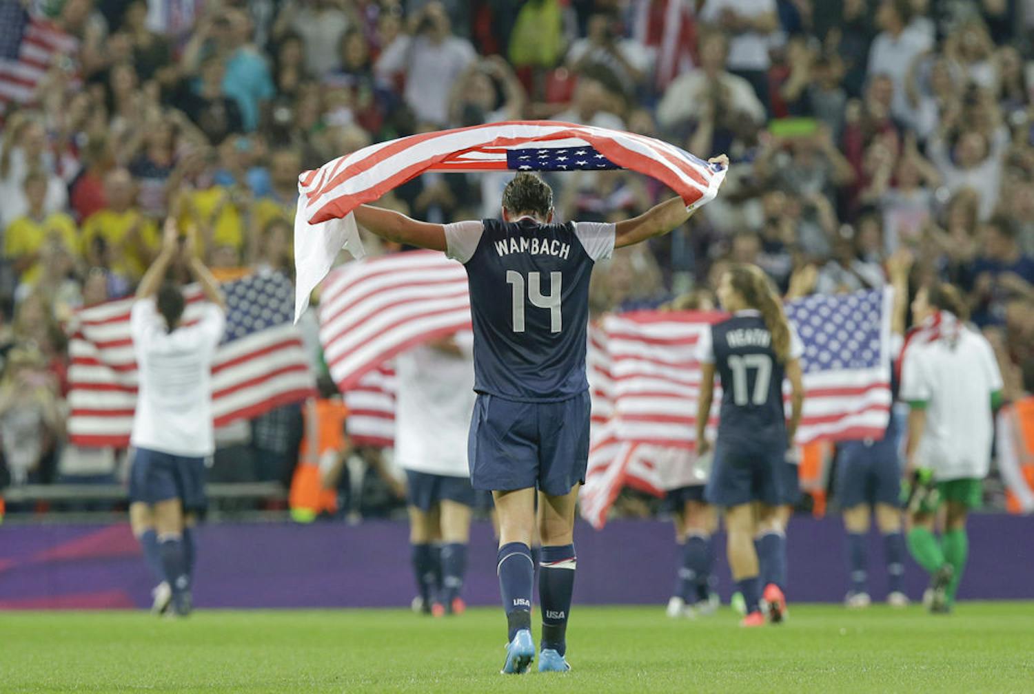 Abby Wambach, draped in an American flag, celebrates with teammates after winning the women's soccer gold medal match against Japan at the 2012 Summer Olympics.