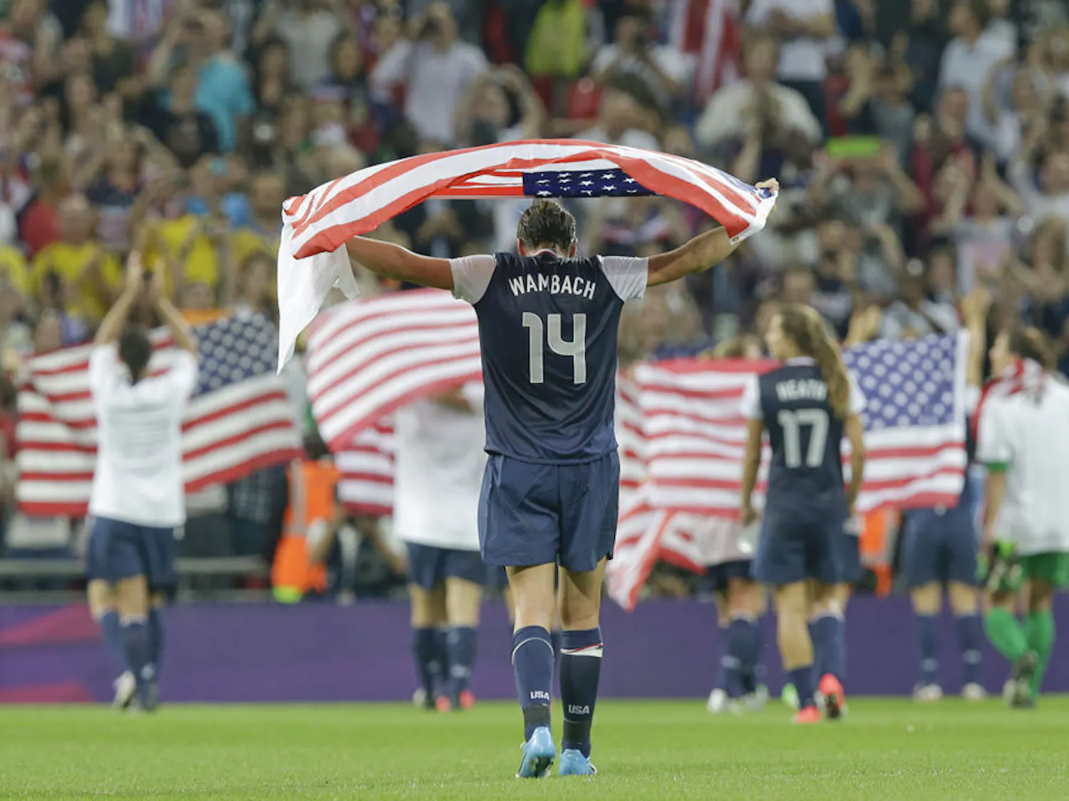 Abby Wambach, draped in an American flag, celebrates with teammates after winning the women's soccer gold medal match against Japan at the 2012 Summer Olympics.