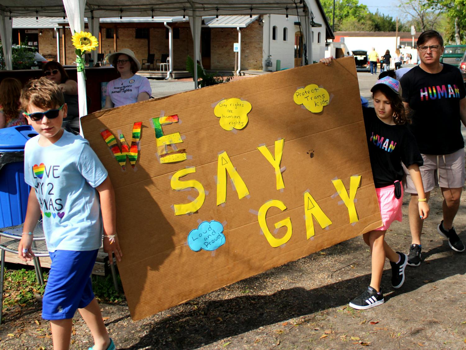Becky Fields, a teacher at Talbot Elementary School, and Fields' two children hold a "We Say Gay" sign to protest Florida's Don't Say Gay bill at Heartwood Soundstage on Saturday, March 19. The bill has passed the state legislature and is on the governor's desk.