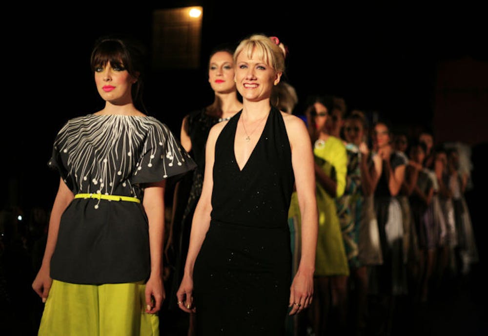 <p>Local fashion designer Jacquelyn Brooks walks alongside models in her clothes after showing her collection at Gainesville Fashion Week.</p>