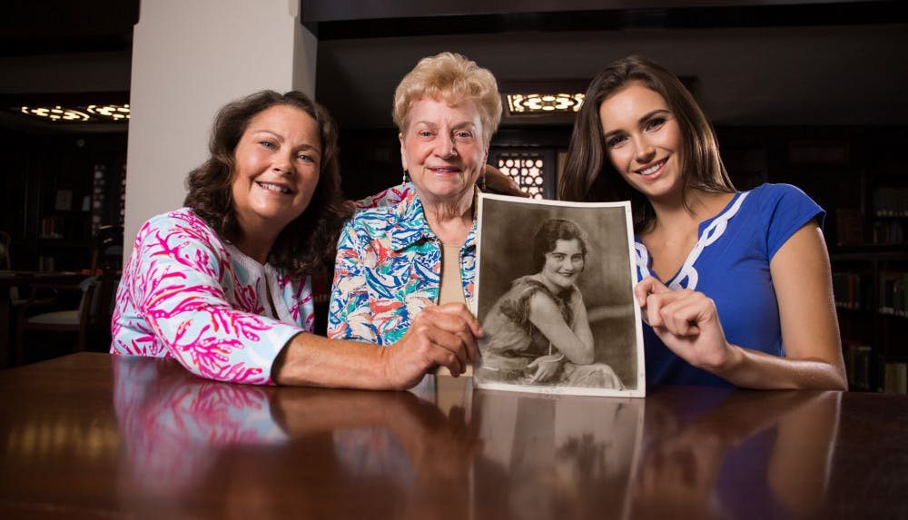 From left: Sara Uhrig, Edna Black Hindson and Hallie Uhrig hold a photo from 1925 of Lassie Goodbread Black. The picture was taken at Smathers Library during a video interview on July 29.