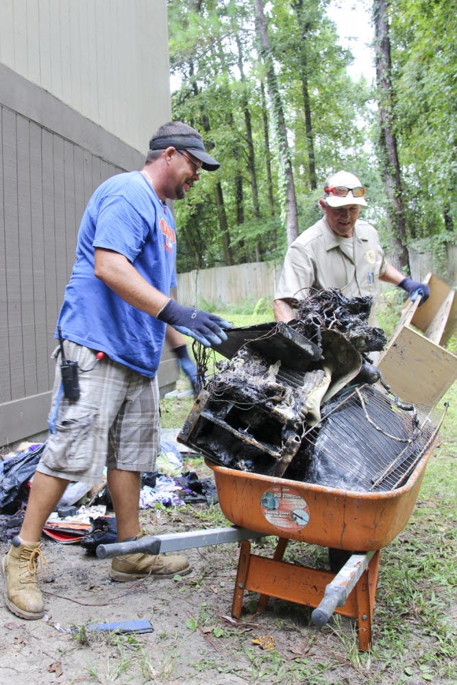 The Aspen Companies’ workers Jeremy Dees, left, and Greg Dove, right, clean up damage from a fire at Majestic Oaks Apartments on Tuesday afternoon.