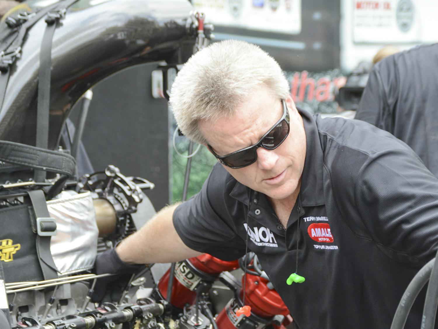 A member of drag racer Terry McMillen’s pit crew services the Top Fuel dragster at a National Hot Rod Association media event near Piesano’s Pizza on Wednesday at noon. Pit crew members at the event demonstrated starting the dragster’s engine, removing it, rebuilding it and then reattaching it before starting it again.