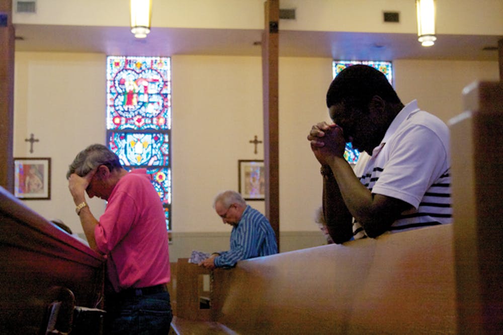<p>St. Augustine Church members pray before noon Mass. According to a recent study, women who regularly attended religious services were 56 percent more likely to be optimistic and 27 percent less likely to show signs of depression.</p>