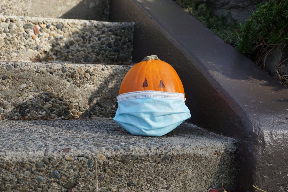 A pumpkin sits alone wearing a mask. Halloween this year will require masks and distance.Photo Illustration by Marek Corsello