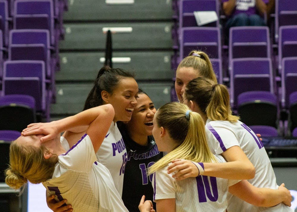 The volleyball team laughs in the huddle after scoring a point.
