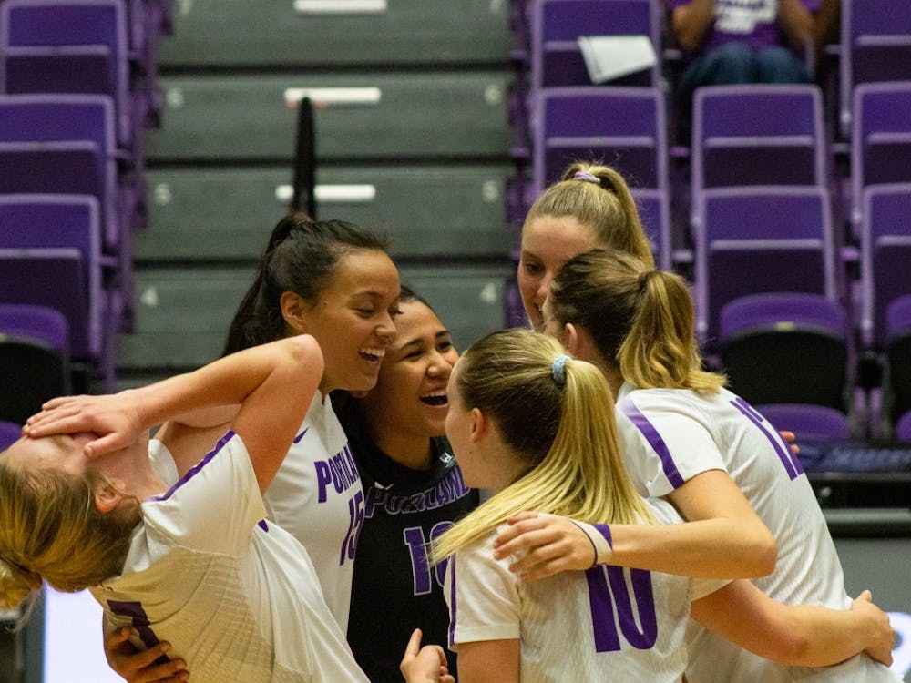 The volleyball team laughs in the huddle after scoring a point.