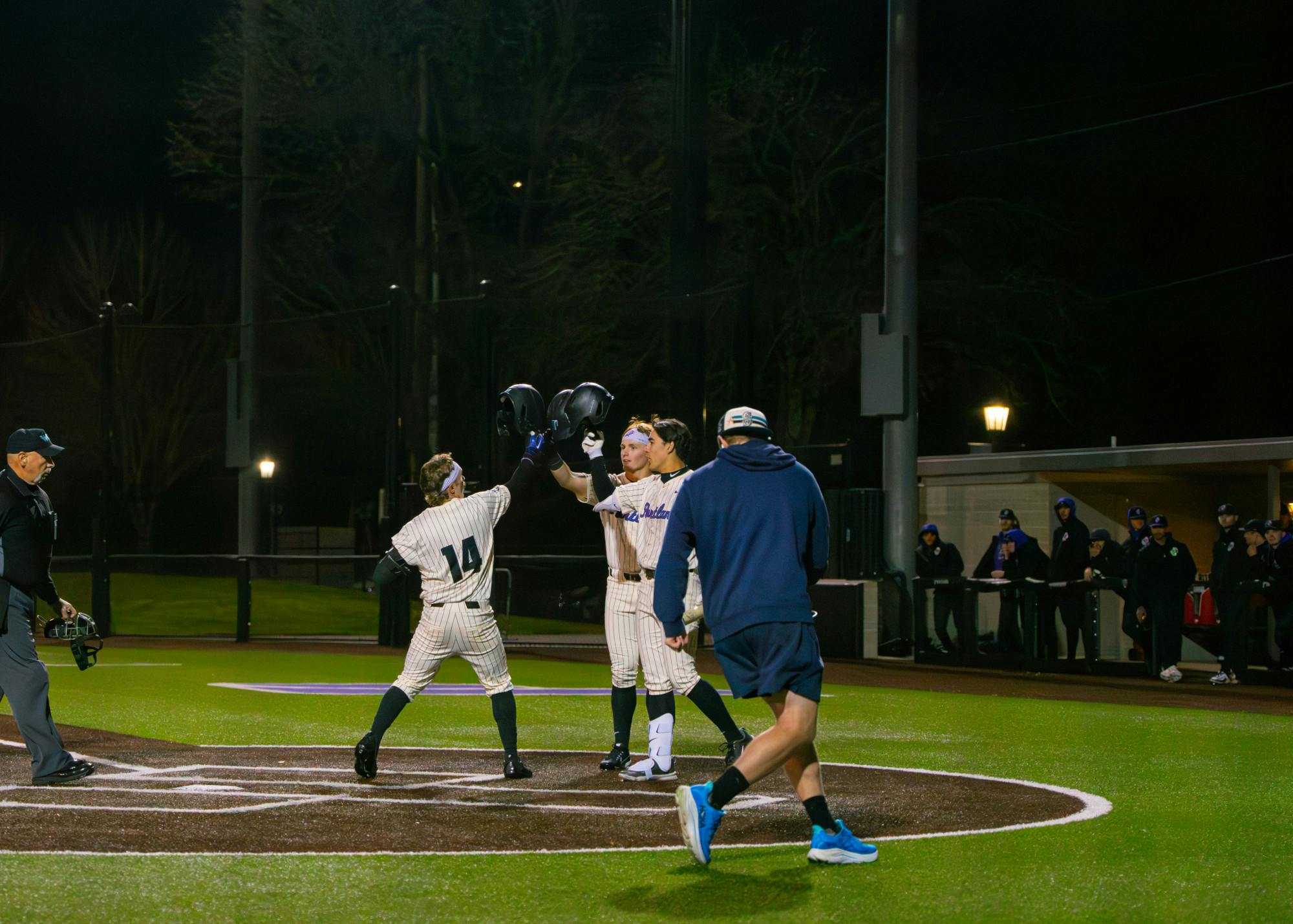 Infielder Jonas Salk crosses home after a two-run blast and celebrates with infielders Nolan Miller and Cole Katayama-Stall.