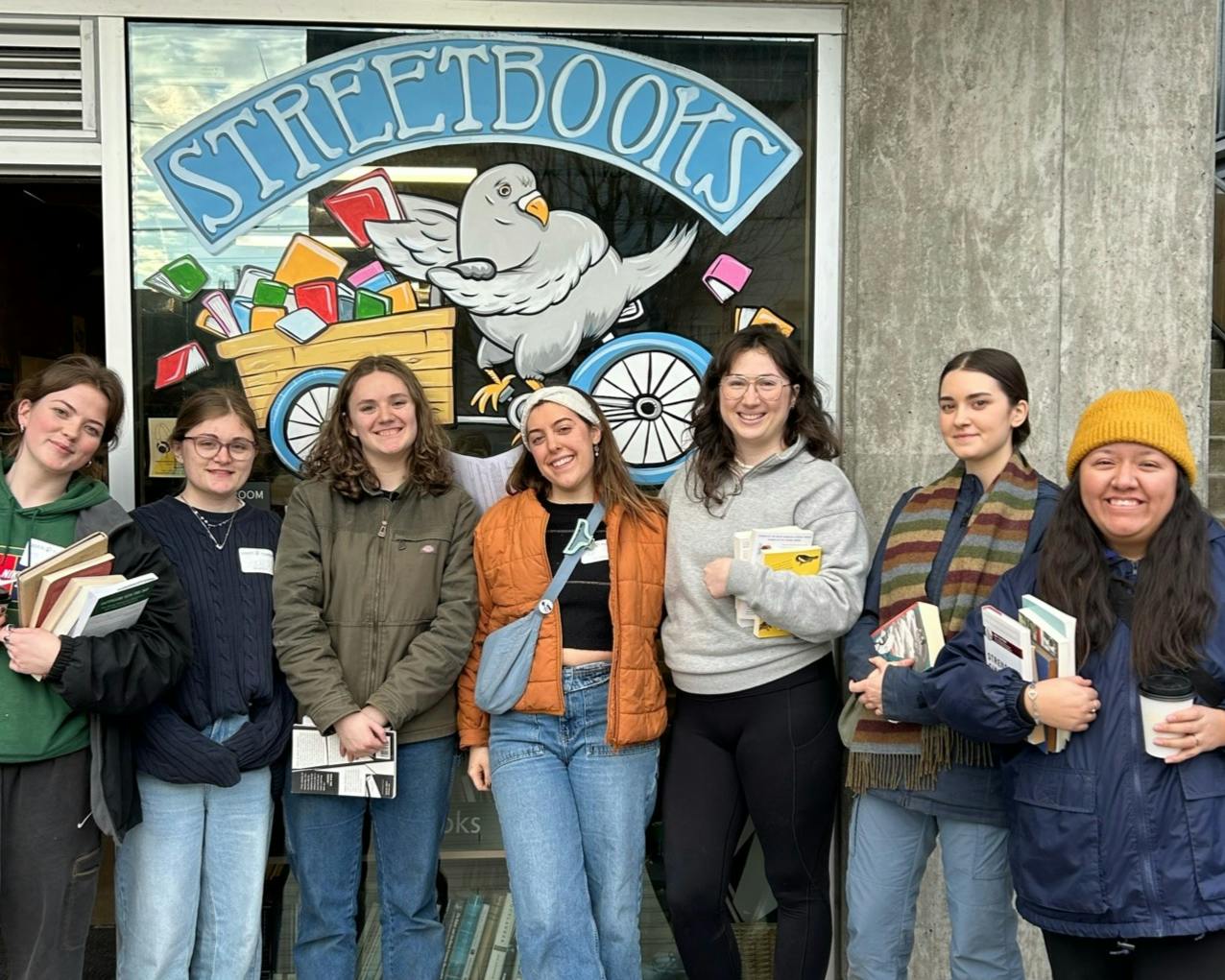 After helping to organize inventory, students pose for a photo in front of Street Books, a local organization in Portland that serves as a mobile library for the unhoused in Portland. The Urban Immersion, January 2025. Photo courtesy of Erin Savoia.