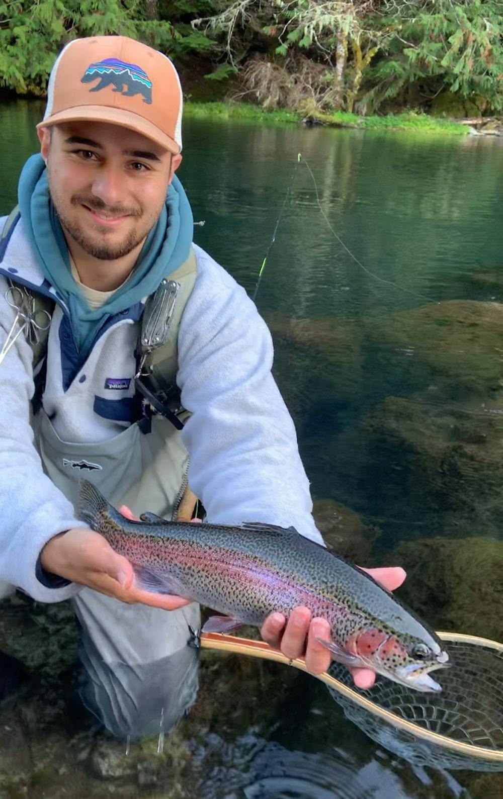 Young fisherman is standing barefeet in water and holding fly rod