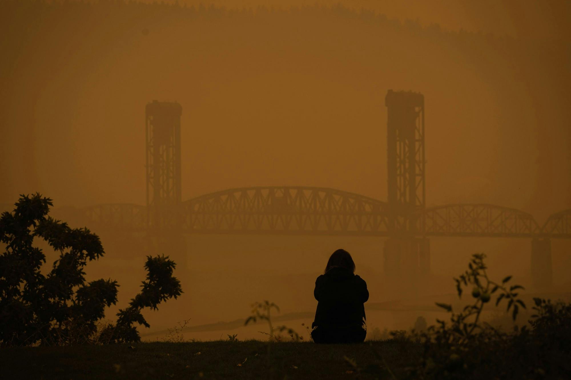 A lone figure stares out at the Burlington Railroad Bridge from The Bluff. Air in Portland will continue to be "very unhealthy" in the coming days.