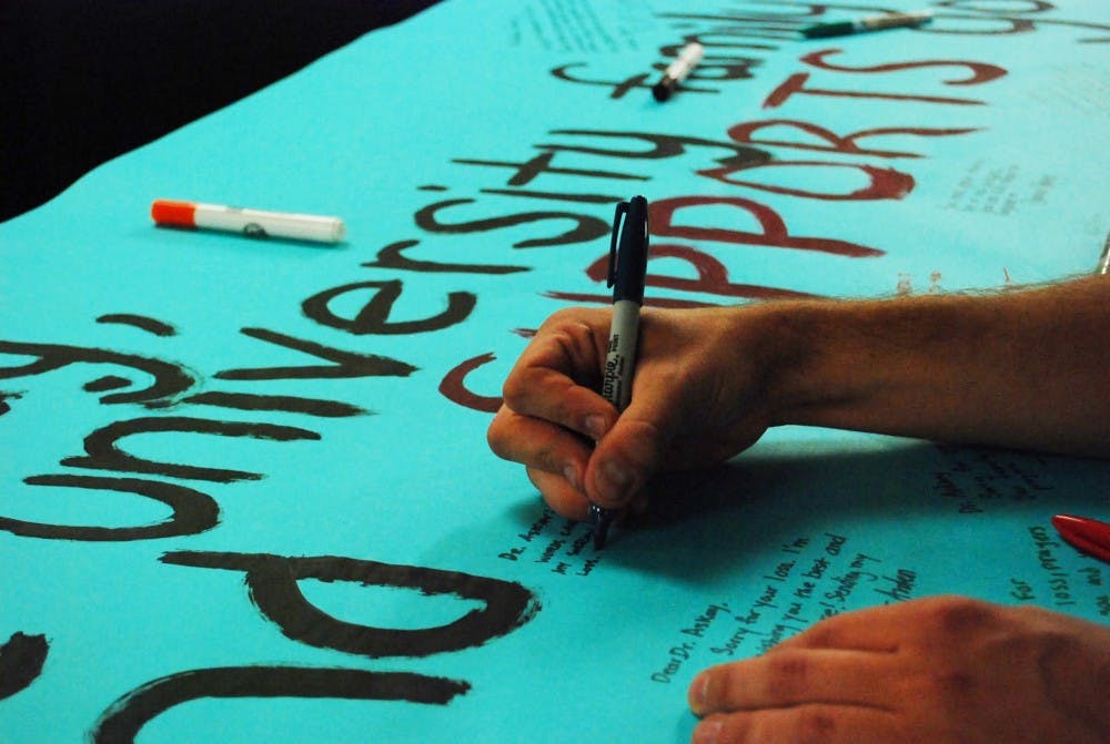  Students sign a card in a show of condolences for philosophy professor Richard Askay, whose son, Soren Bryan-Askay, died yesterday. Bryan-Askay worked as a custodian at UP. Photo by David DiLoreto