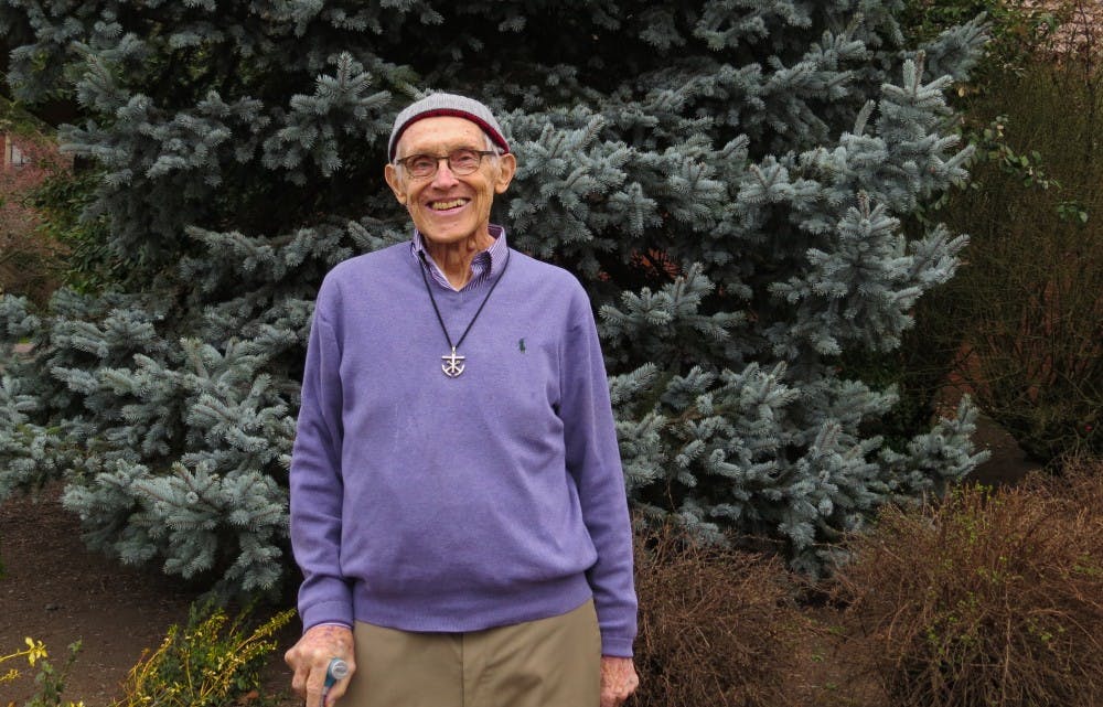 Fr. Claude with the greenery on the side of the chapel, one of his favorite places on campus. 
