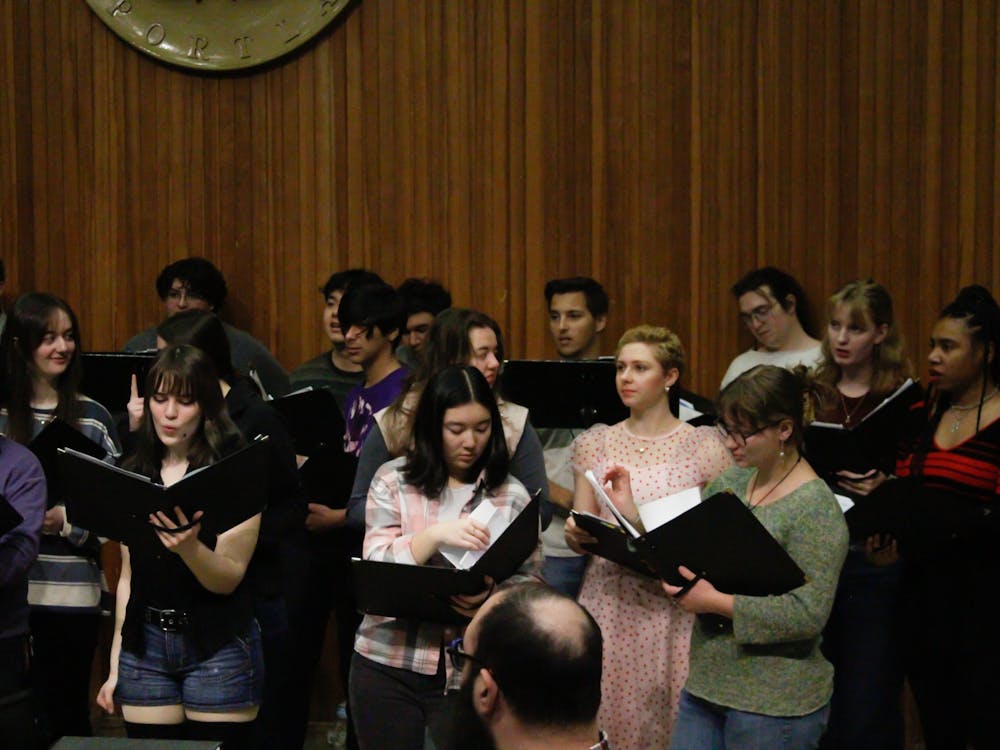 University Singers stand talking with each other and preparing their music