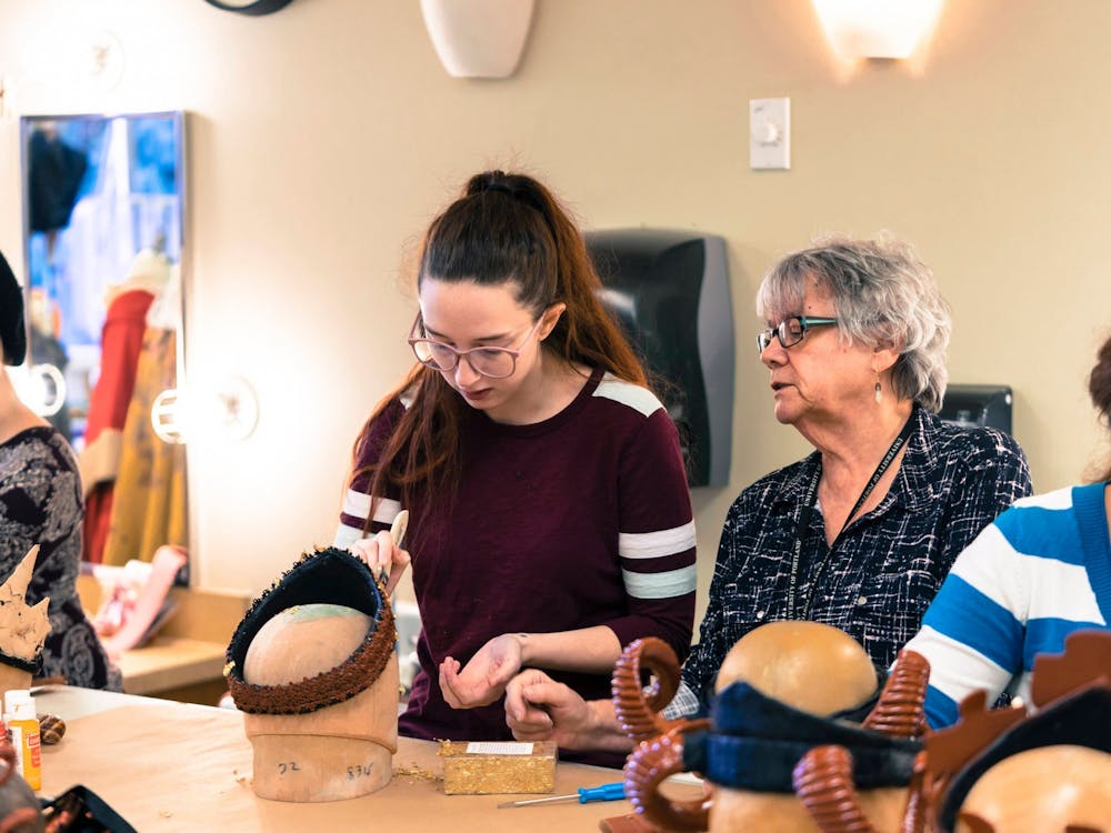 Amanda Ryan (left) coats a crown with gold leaf as costume director Sue Bonde (right) observes her work.
