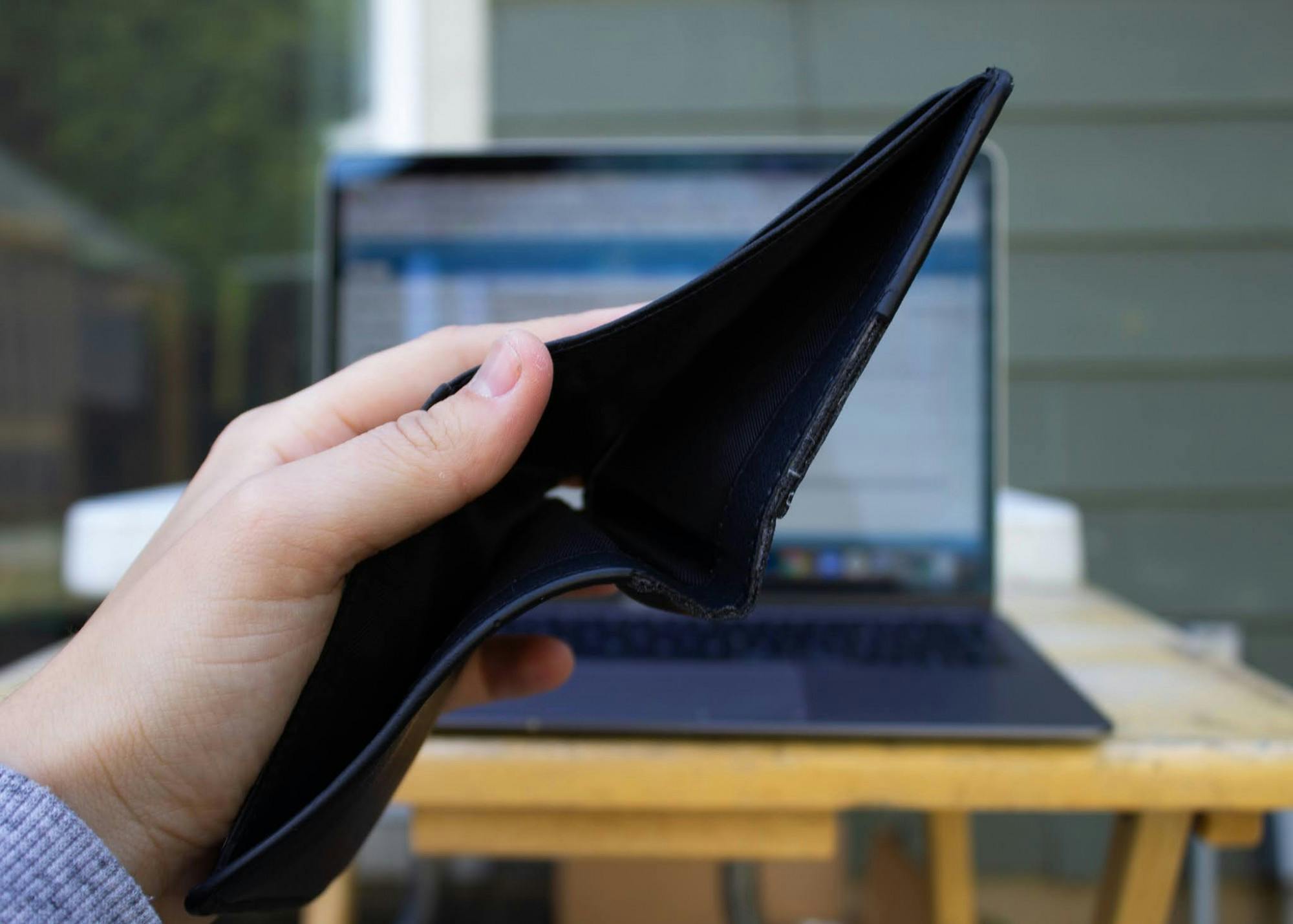 An empty wallet held in front of an open laptop. Additional scholarships could help students fund this year's tuition.Photo illustration by Emma Sells/The Beacon