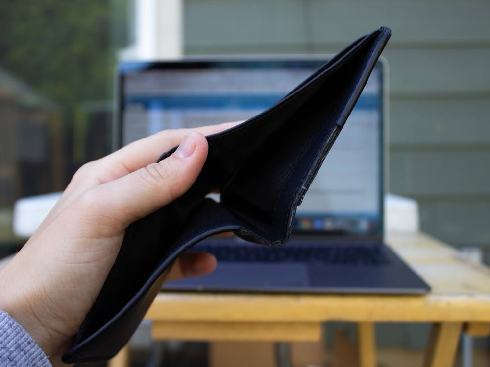 An empty wallet held in front of an open laptop. Additional scholarships could help students fund this year&#x27;s tuition.Photo illustration by Emma Sells/The Beacon
