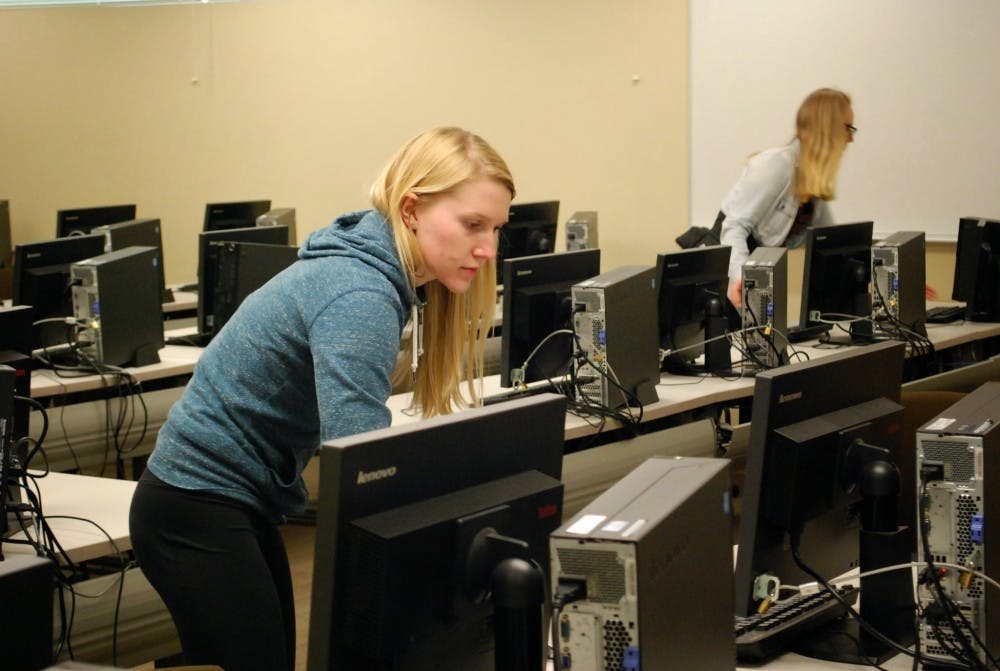  College Ecology Club members turn off computer monitors in Shiley Hall. Photo by The Beacon.