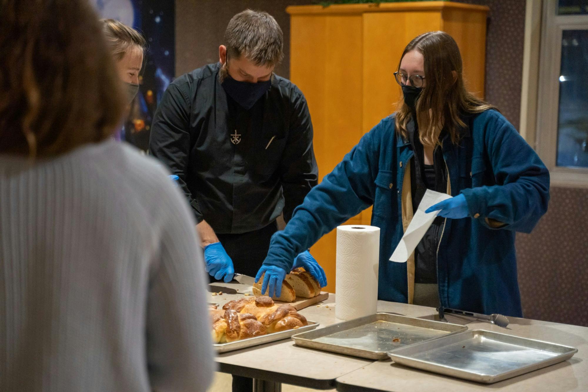 Mehling residents and Father Jim hand out bread in the Mehling Ballroom.