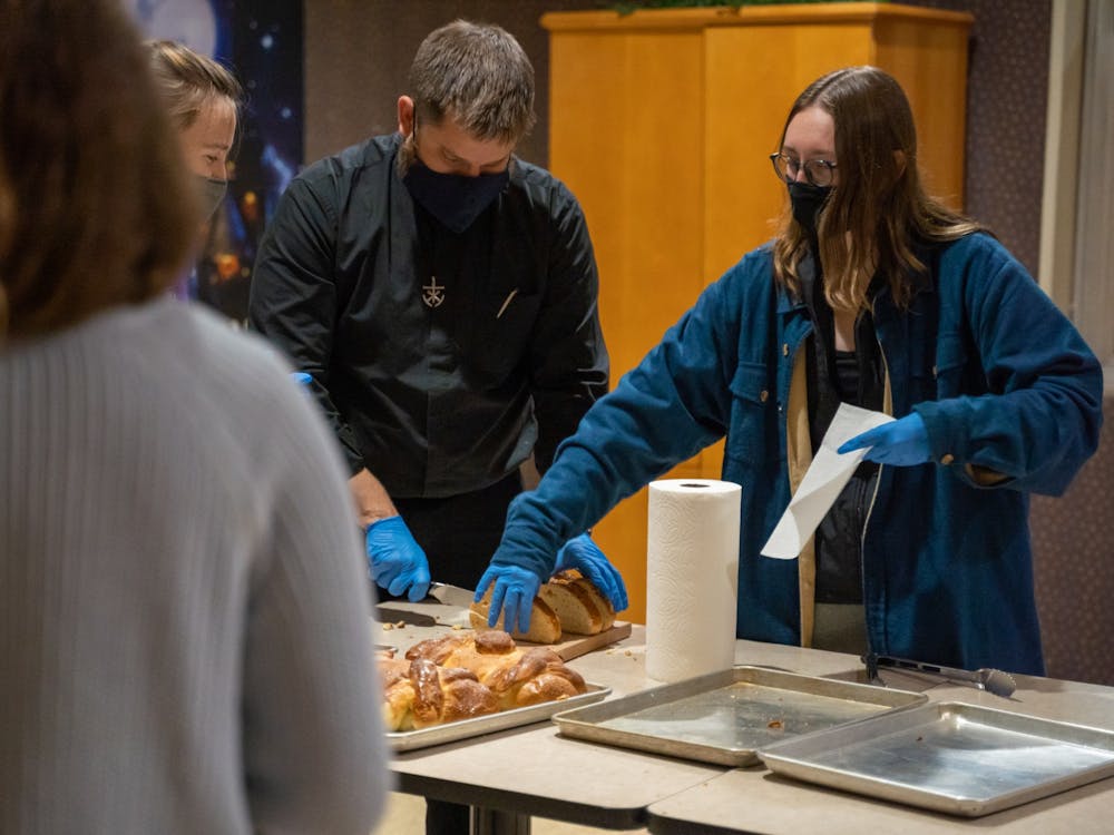 Mehling residents and Father Jim hand out bread in the Mehling Ballroom.