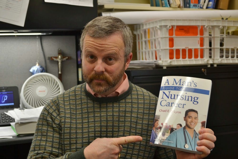  Nursing professor Chad O'Lynn holds his book, "A Man's Guide to Nursing." O'Lynn says one of the reasons nursing school is difficult for men is because of the stereotypes that depict it as a female profession. Photo by David DiLoreto