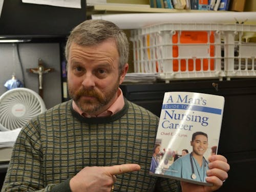  Nursing professor Chad O'Lynn holds his book, "A Man's Guide to Nursing." O'Lynn says one of the reasons nursing school is difficult for men is because of the stereotypes that depict it as a female profession. Photo by David DiLoreto