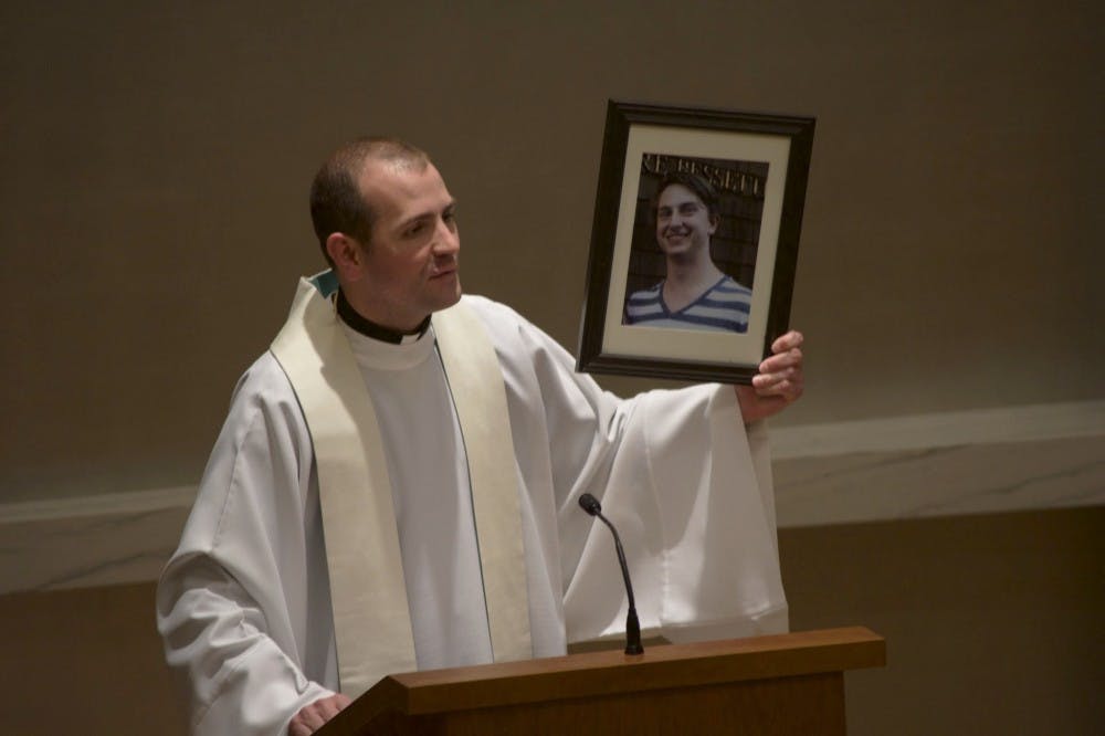  Fr. Mark DeMott holds a picture of Michael Eberitzsch II during a memorial in the Chapel of Christ the Teacher on Tuesday. Eberitzsch was killed in a car accident March 6. Photo by David DiLoreto