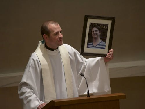  Fr. Mark DeMott holds a picture of Michael Eberitzsch II during a memorial in the Chapel of Christ the Teacher on Tuesday. Eberitzsch was killed in a car accident March 6. Photo by David DiLoreto