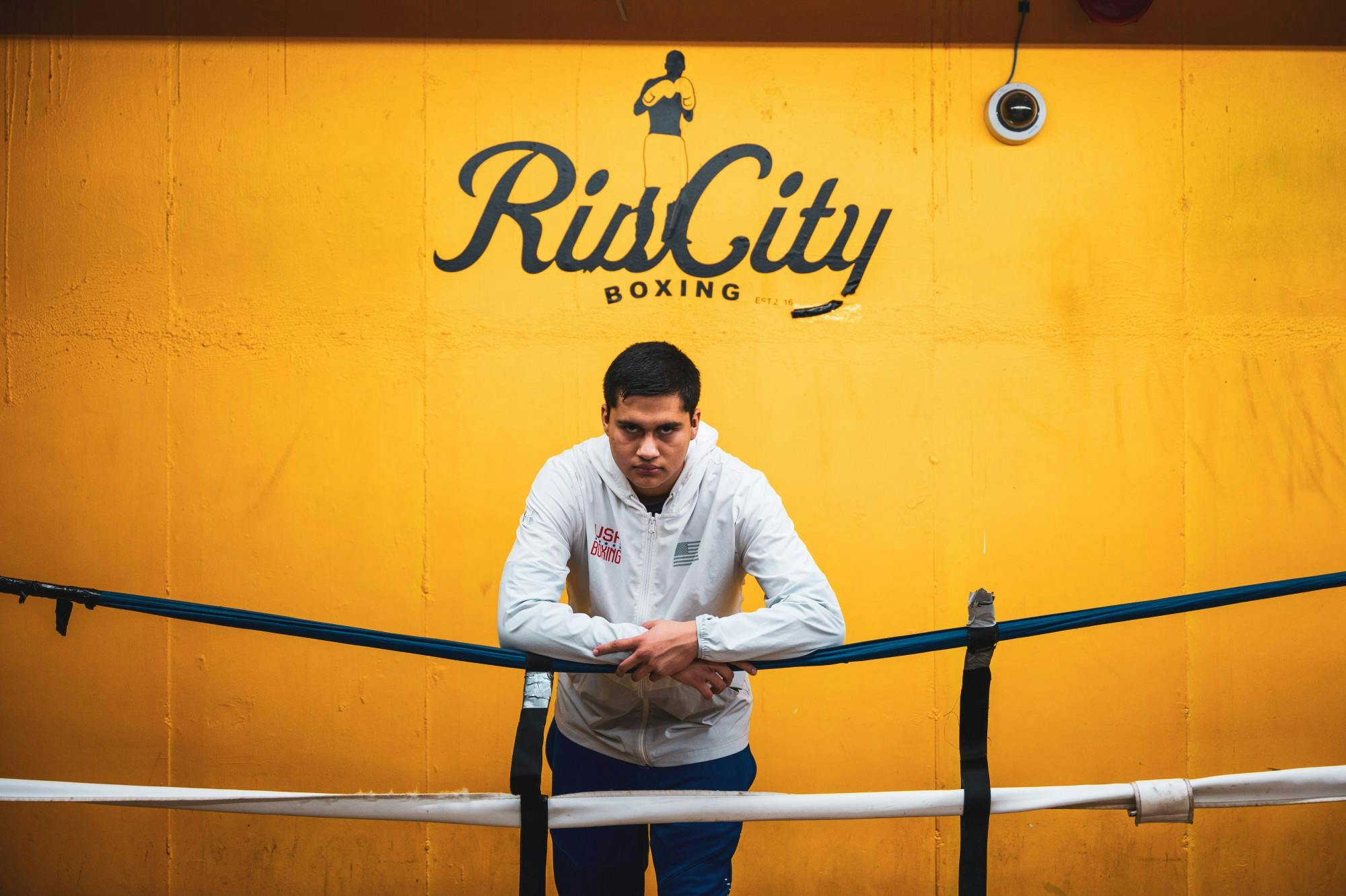 Santiago leaning on boxing ring. He and his father run the gym.
