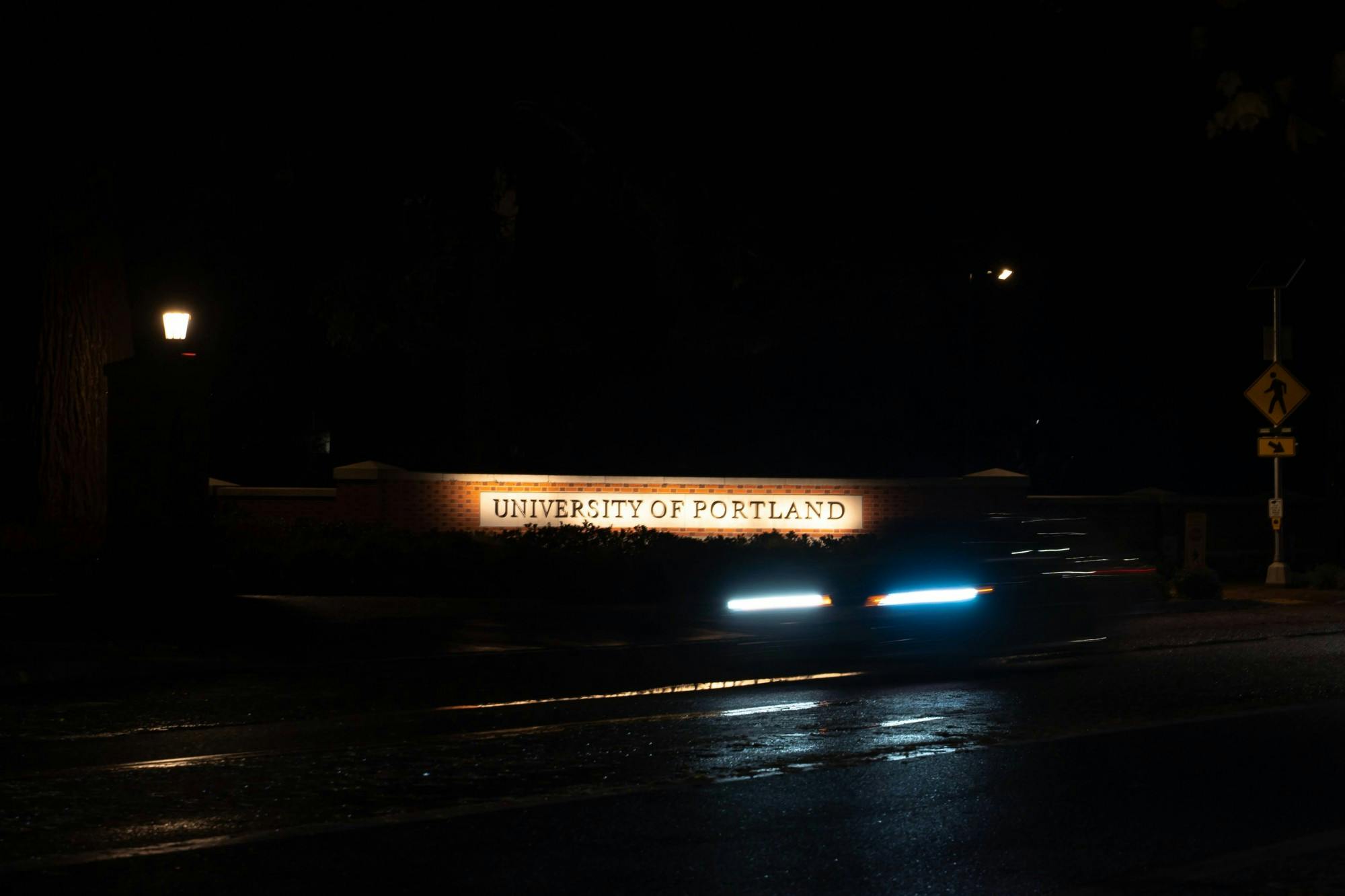A car drives past the University of Portland entrance at night. Many UP students live in  houses and apartments outside of the campus in University Park.
