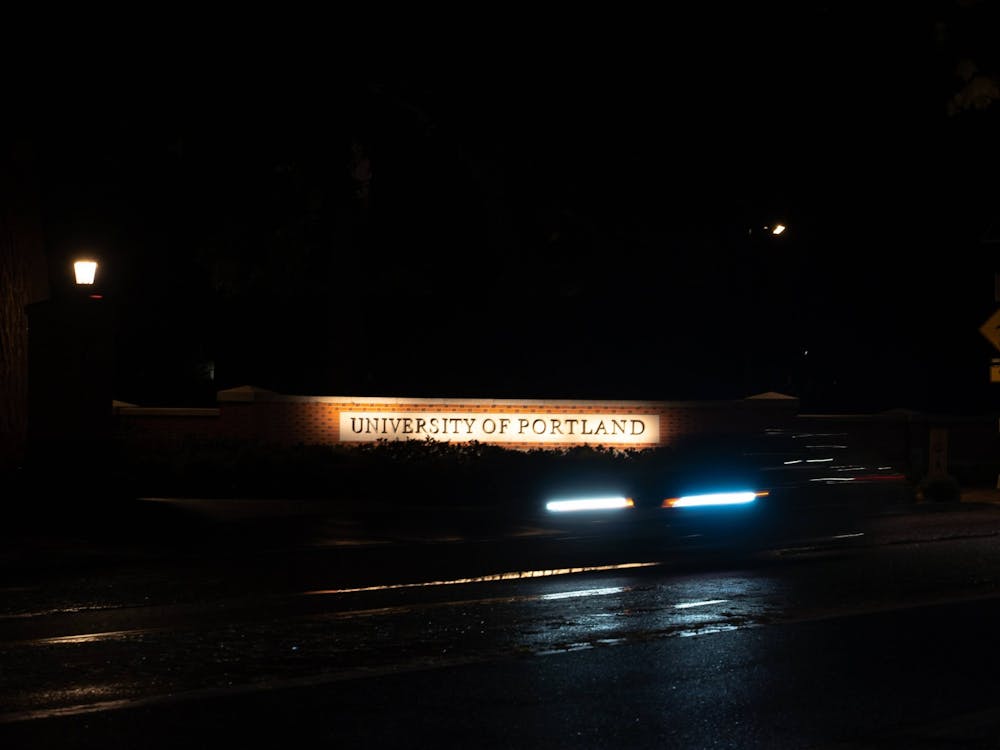 A car drives past the University of Portland entrance at night. Many UP students live in  houses and apartments outside of the campus in University Park.