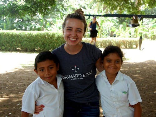  Junior nursing major Cassie Slayter takes a break from raking grass to play with a couple of Nicaraguan children during their school recess. Photo courtesy of Cassie Slayter.